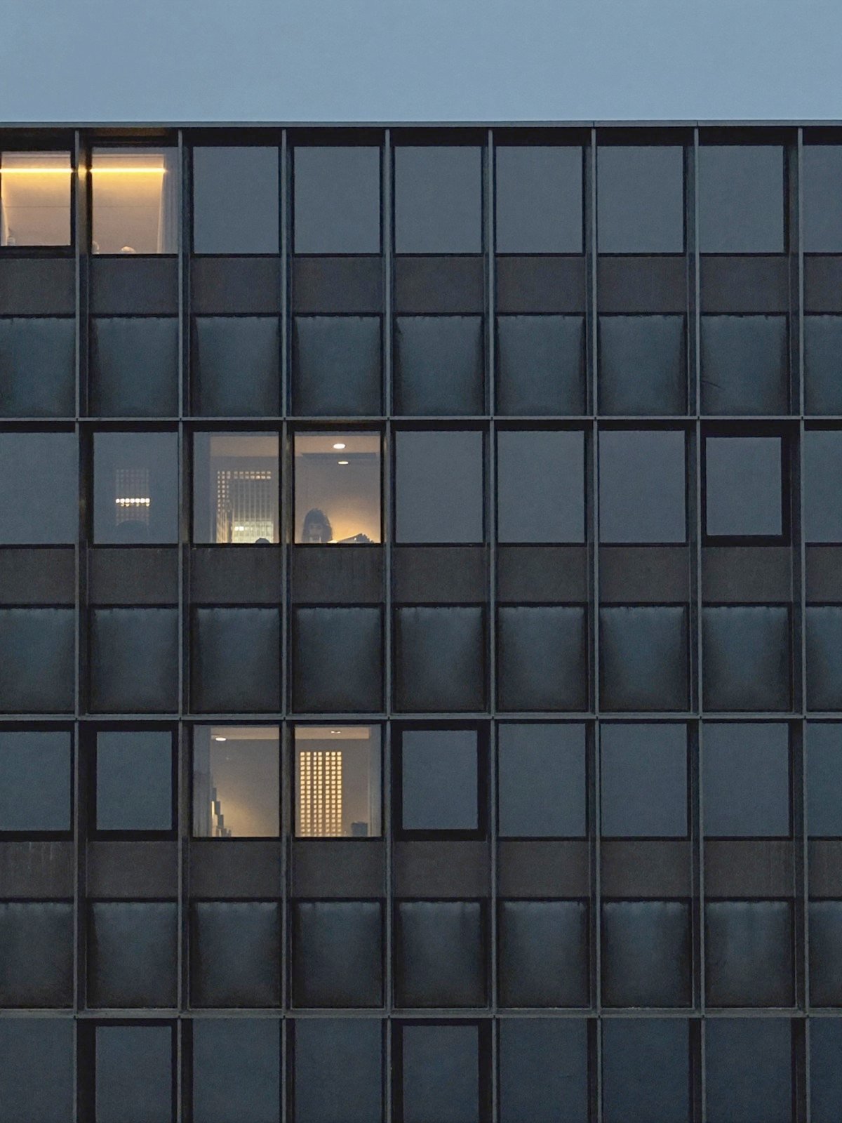 Office facade at dusk with a few lit windows