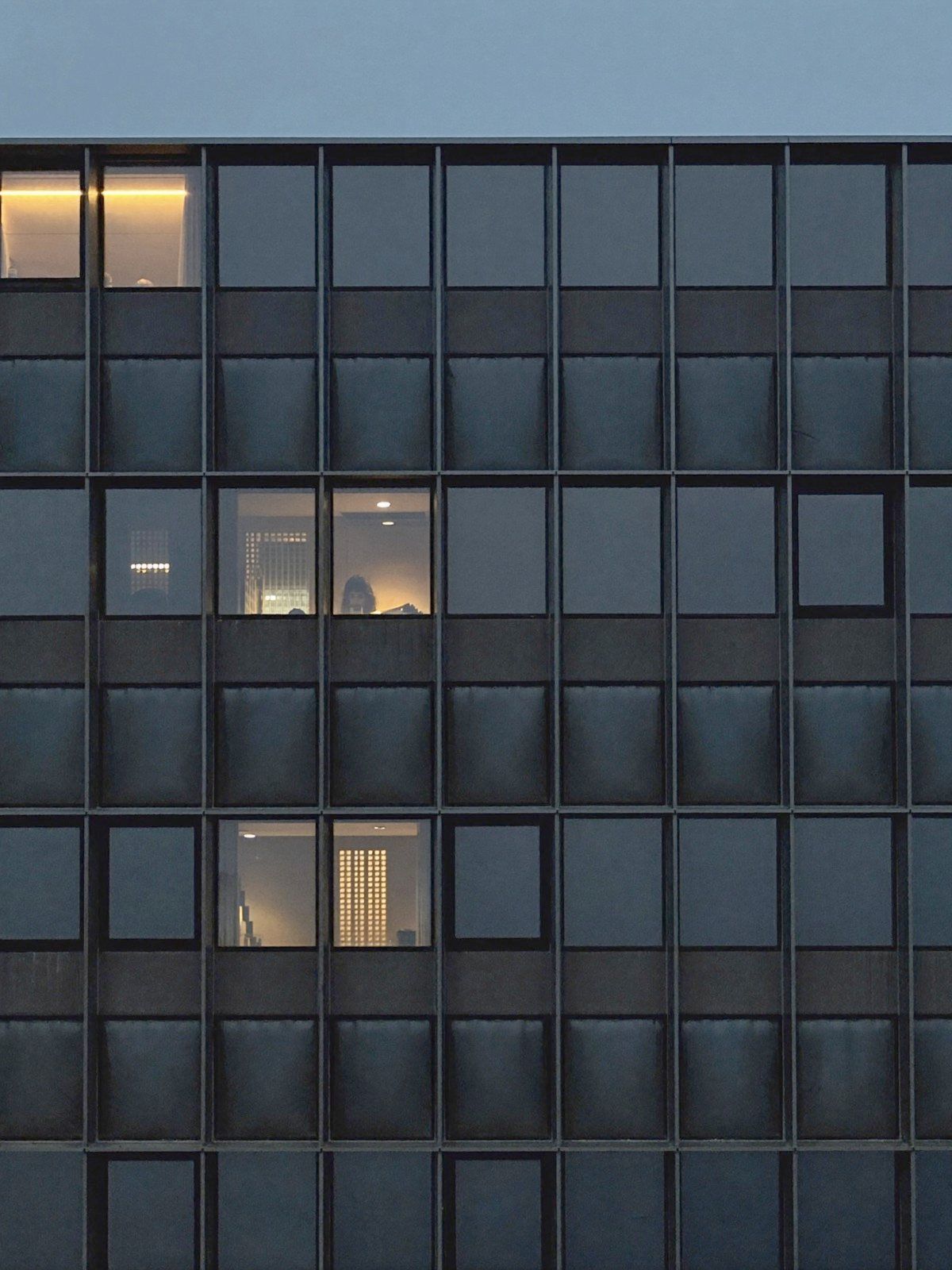 Office facade at dusk with a few lit windows